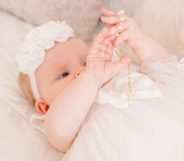 Baby holding 14K Gold-Plated White Baby Rosary Baptism Gift